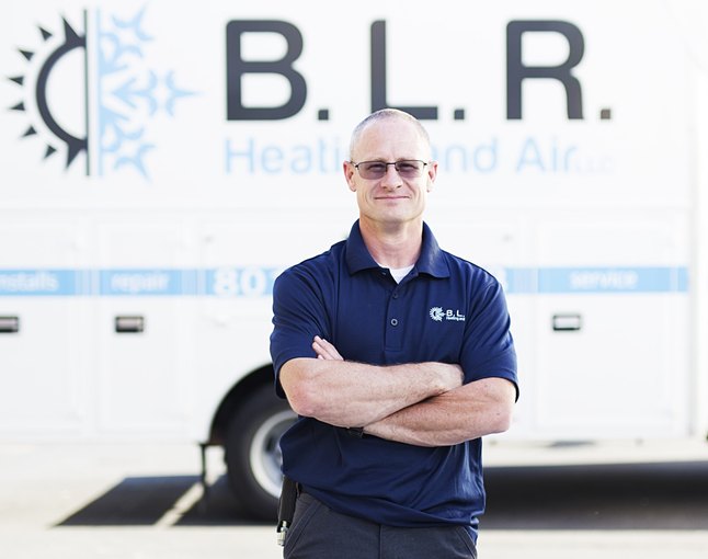 Byron Rodgers, owner of B.L.R. Heating & Air, in a branded polo in front of the company van