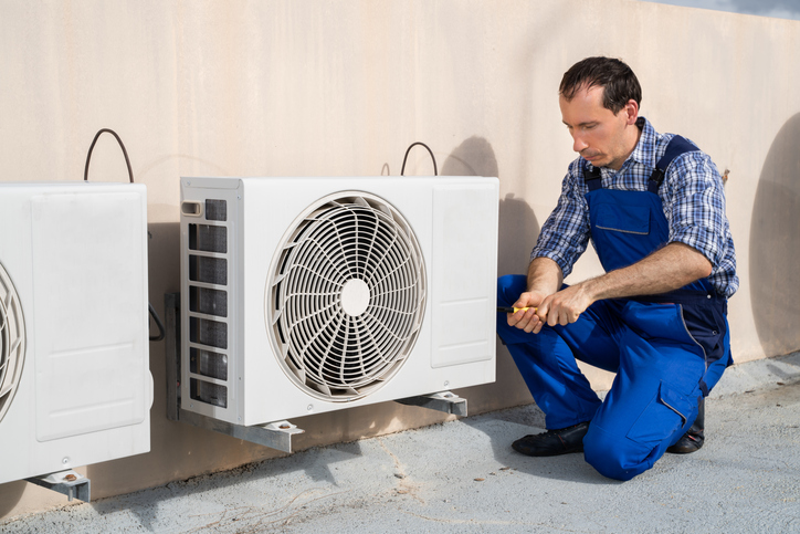 Technician servicing outdoor air conditioning equipment