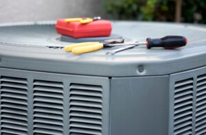 Air conditioning unit with tools including screwdriver and pliers, illustrating HVAC maintenance and repair for homeowners in Woods Cross.