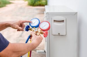 Technician checking AC refrigerant levels with pressure gauges on a residential air conditioning unit in Woods Cross.