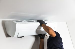 HVAC technician installing a ceiling-mounted air conditioning unit, emphasizing professional air conditioning services for homeowners in Woods Cross.