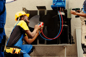 Technician repairing air conditioner fan motor with tools, focusing on HVAC maintenance in residential setting.
