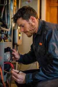 Home 25 Homeowner checking a thermostat and inspecting a furnace during a troubleshooting check